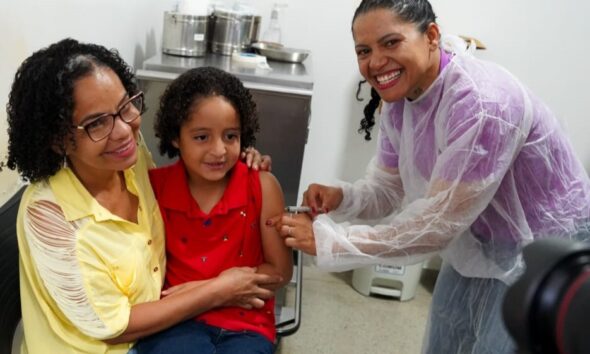 Goiânia e Aparecida antecipam ampliação da vacinação contra gripe - criança no colo da mãe recebendo vacina