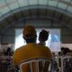 Governo de Goiás leva Cine Leitura do Bem a mais quatro municípios - público assistindo a sessão de cinema do projeto. Em primeiro plano, pai com bebê nos braços assistindo ao filme